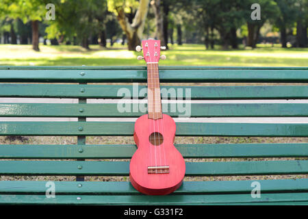 Un ukulele su una panchina nel parco. All'esterno. Foto Stock