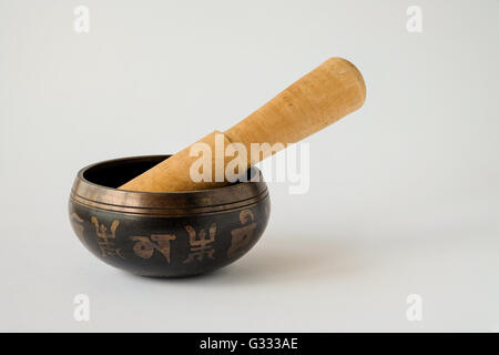 Bronzo decorativo Tibetan Singing Bowl con un mazzuolo di legno. Ogni secondo simbolo è un carattere tibetano che compongono il mantra "om Foto Stock