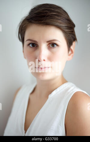 Affascinante di capelli corti giovane donna senza trucco su sfondo bianco Foto Stock