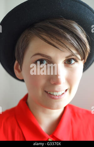 Affascinante giovane donna in hat senza trucco su sfondo bianco Foto Stock