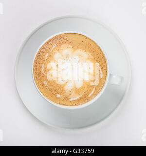 Delizioso cappuccino in una tazza bianca sulla piastra su sfondo bianco. Close up vista dall'alto. Foto Stock