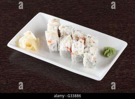Rotoli di sushi su una piastra con tonno e lo zenzero in legno marrone scuro e tabella. Vista laterale. Foto Stock