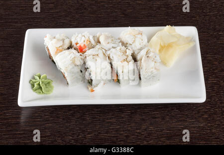 Rotoli di sushi su una piastra con tonno e lo zenzero in legno marrone scuro e tabella. Vista laterale. Foto Stock