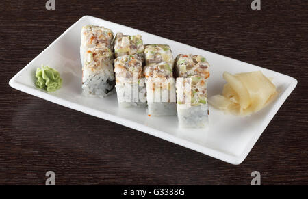 Rotoli di sushi su una piastra con tonno e lo zenzero in legno marrone scuro e tabella. Vista laterale. Foto Stock