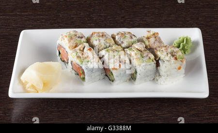 Rotoli di sushi su una piastra con tonno e lo zenzero in legno marrone scuro e tabella. Vista laterale. Foto Stock