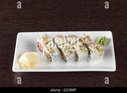Rotoli di sushi su una piastra con tonno e lo zenzero in legno marrone scuro e tabella. Vista laterale. Foto Stock