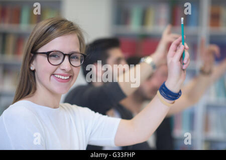 Gruppo di studenti smart alzare le mani fino in aula scolastica sulla classe Foto Stock