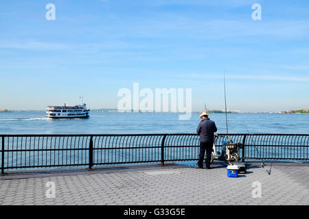 Un pescatore di pesca sul fiume Hudson in Battery Park City. Foto Stock