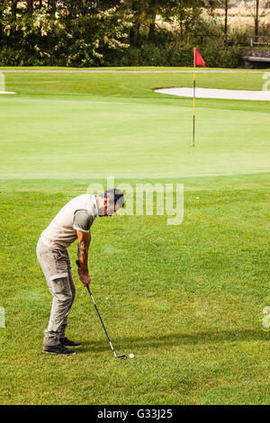 Un giocatore di golf facendo uno swing su una vivace bellissimo campo da golf Foto Stock