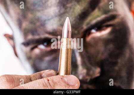 Un tiratore scelto o sharpshooter indossando esercito faccia camouflage vernice e tenendo un bullet isolate su uno sfondo bianco Foto Stock