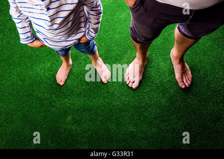 Irriconoscibile il padre e il figlio in piedi contro verde artificiale Foto Stock