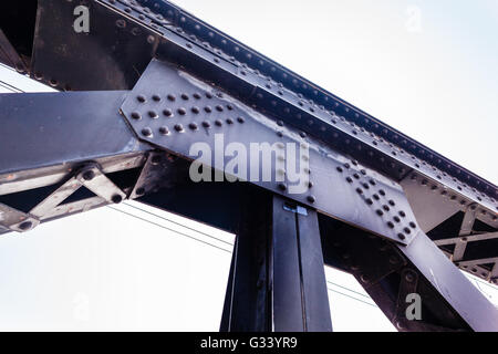 Un forte rivettato travi in acciaio struttura di un ponte ferroviario Foto Stock