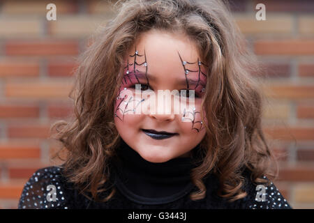 Bambina con spider web dipinto sul volto guardando la fotocamera. Halloween Foto Stock