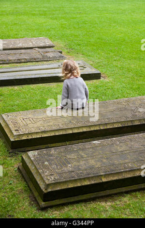 Bambino / bambini / Kids / kid esplora intorno tombe nel chiostro Garth / chiostri giardino presso la Cattedrale di Lincoln, Lincoln. Regno Unito. Foto Stock