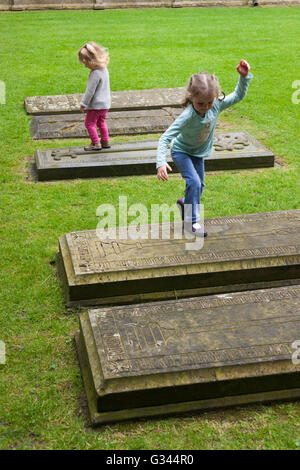 Bambino / bambini / Kids / kid esplora intorno tombe nel chiostro Garth / chiostri giardino presso la Cattedrale di Lincoln, Lincoln. Regno Unito. Foto Stock