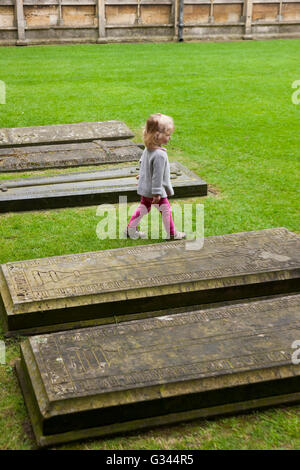 Bambino / bambini / Kids / kid esplora intorno tombe nel chiostro Garth / chiostri giardino presso la Cattedrale di Lincoln, Lincoln. Regno Unito. Foto Stock