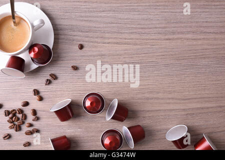 Tazza di caffè espresso servito con cialde e capsule su marrone tavolo in legno. Vista superiore Foto Stock