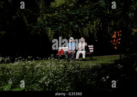 Due pensionati godendo il tempo in estate su una panchina nel parco in Northumberland città mercato di Morpeth Foto Stock