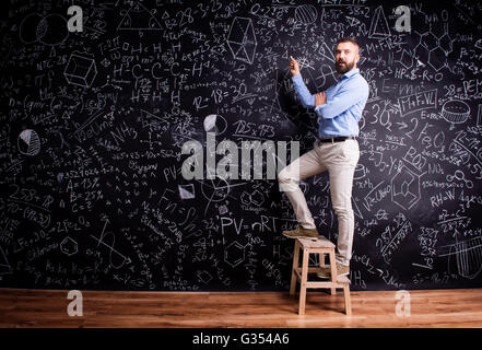 L'uomo la scrittura sulla grande lavagna con i simboli matematici Foto Stock