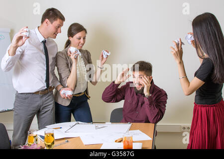 Persone che lanciano sui documenti di un collega in ufficio Foto Stock