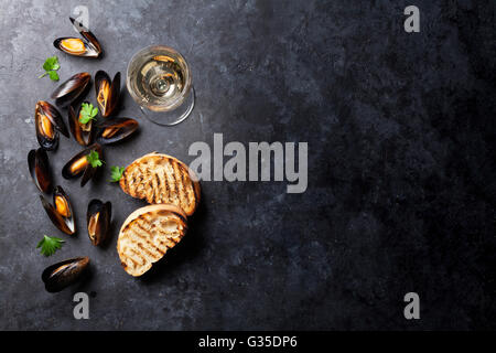 Cozze, crostini di pane e vino bianco sul tavolo di pietra. Vista con lo spazio di copia Foto Stock