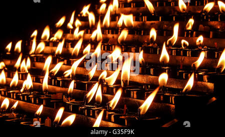 La preghiera, offrendo sacrificale o memorial candele con effetto bokeh di fondo in una chiesa Foto Stock