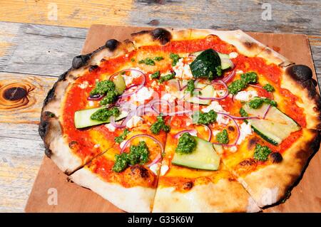 A legna per pizza vegetariana su una tavola in legno rustico Foto Stock