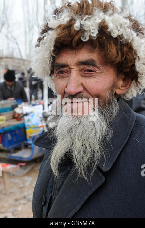 La provincia cinese dello Xinjiang, giorno di mercato nel villaggio di uighur Langar vicino a Kashgar , l' uomo con la divertente copricapo e barba grigia, unica faccia Foto Stock