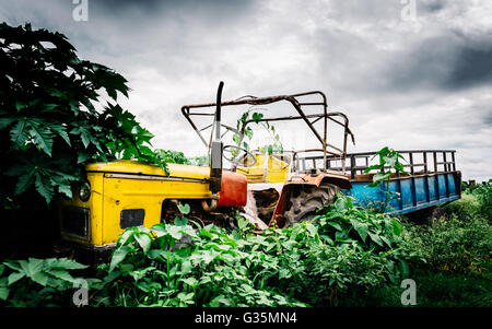Abbandonato il giallo vintage il trattore con il rimorchio blu in Nepal Foto Stock