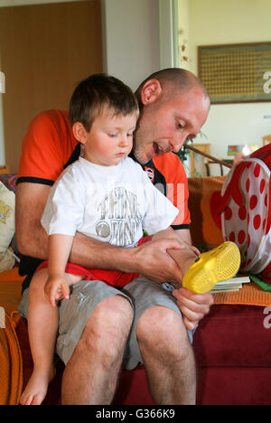 Mendrisio, Svizzera - 20 giugno 2008: padre mettendo le scarpe a suo figlio a casa Foto Stock