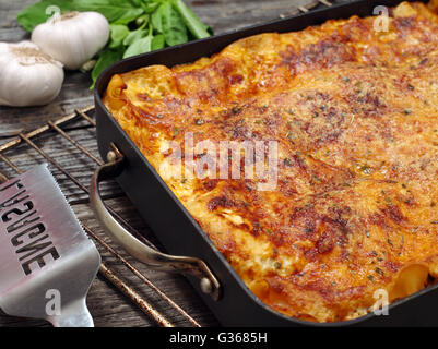 Foto di un pane appena sfornato lasagne, seduto su un vecchio tavolo di legno. Foto Stock