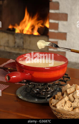 Foto di pane essendo immersi nel formaggio fuso nel recipiente fonduta. Foto Stock