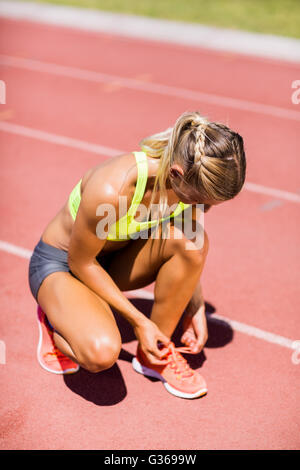 Atleta femminile la sua legatura lacci della scarpa sulla via di corsa Foto Stock