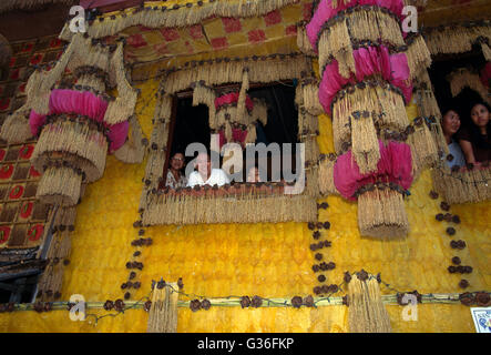 Filippine Lucban Pahiyas Festival persone guardare fuori delle finestre decorate per la festa in onore del santo patrono degli agricoltori Sant Isidoro l'Operaio Foto Stock