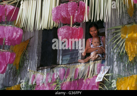 Filippine Lucban Pahiyas Festival donna e bambino guardando fuori delle finestre decorate per la festa in onore del santo patrono degli agricoltori Sant Isidoro l'Operaio Foto Stock