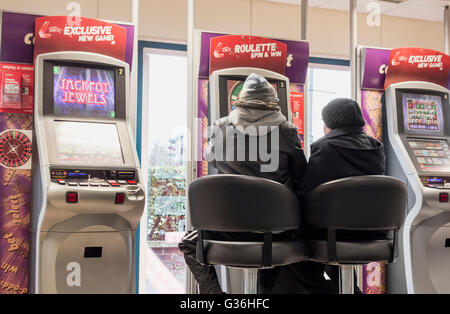 L uomo e la donna a Roulette macchina da gioco (FOBT fixed odds betting terminale) in Ladbrokes Bookmakers in Inghilterra, Regno Unito Foto Stock