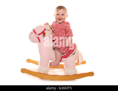 Baby girl giocando su un cavallo a dondolo intaglio Foto Stock