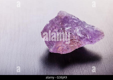 Immagine ravvicinata di un frammento del minerale di ametista su di una superficie scura Foto Stock