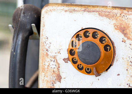Vecchio arrugginito rotante vintage telefono a pagamento per uso pubblico. Vecchio telefono a pagamento con moneta slot su una parete. Foto Stock