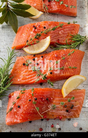 Salmone fresco fette cosparso con erbe e spezie sulla superficie di pietra Foto Stock