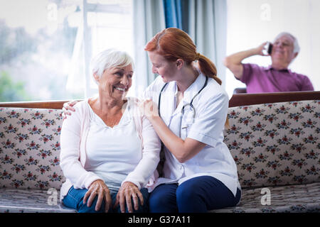 Senior donna e medico donna interagenti in salotto Foto Stock