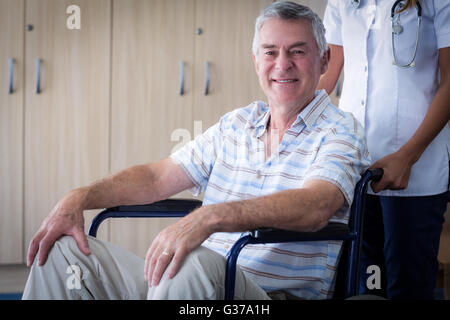 Medico donna che trasportano senior uomo sulla sedia a rotelle Foto Stock
