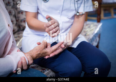 Test medico pazienti un livello di glucosio utilizzando un glucometro digitale Foto Stock