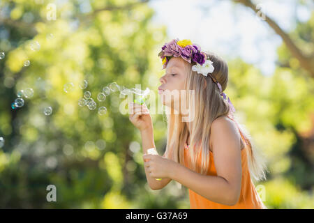 Ragazza giovane soffiare bolle attraverso il bubble wand Foto Stock