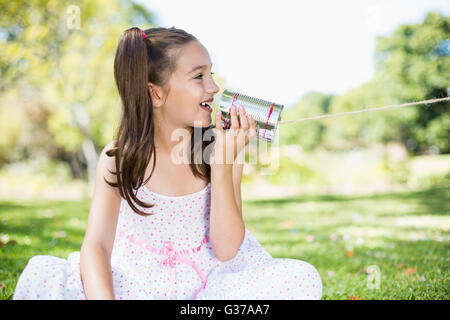 Ragazza giovane che parla attraverso la scatoletta di latta telefono Foto Stock