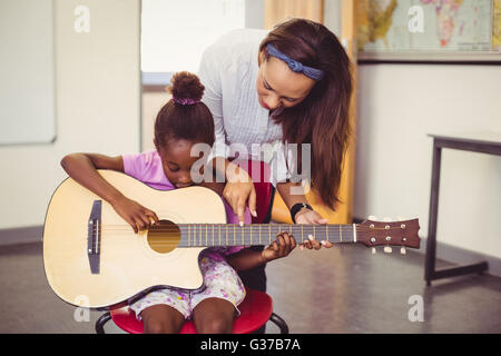 Insegnante assistere una ragazza a suonare la chitarra in aula Foto Stock