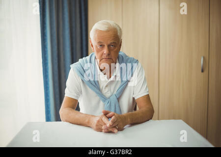 Triste senior uomo seduto a tavola Foto Stock