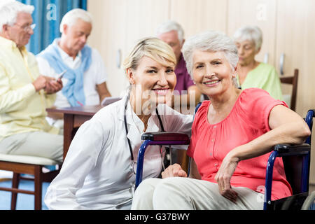 Senior donna seduta su una sedia a rotelle Foto Stock