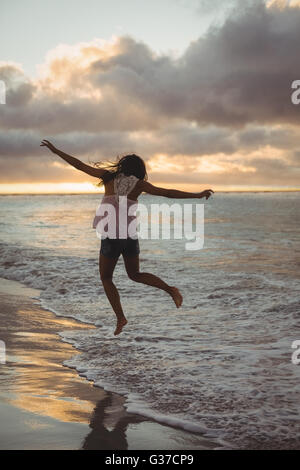 Donna salta sulla spiaggia Foto Stock
