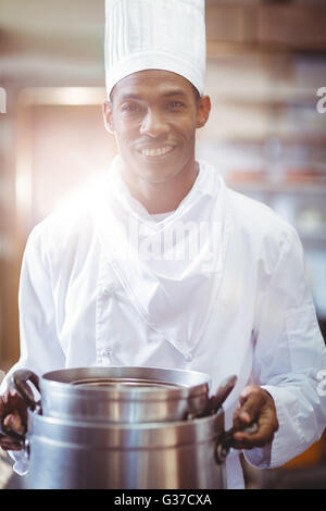 Sorridente chef nella cucina azienda pentola di cottura Foto Stock